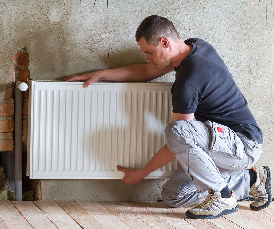 Ein Handwerker installiert einen Heizkörper